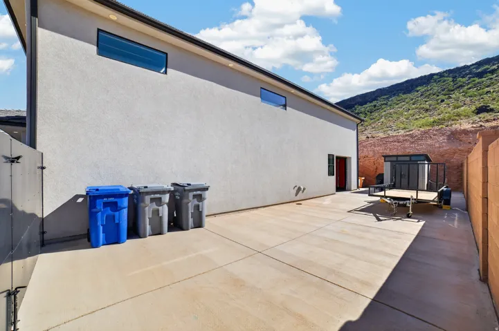 Paved concrete side yard with a red entry door, a detached storage shed, and a privacy fence