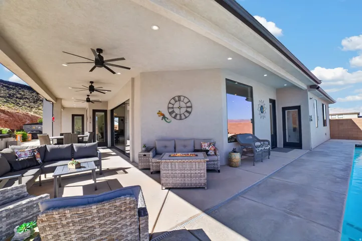 Expansive covered patio with multiple ceiling fans, recessed lighting, and direct access to the outdoor pool