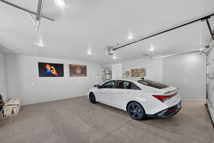 Two-car garage with concrete flooring, recessed lighting, and a white garage door