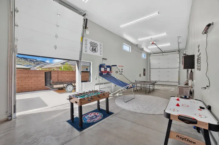 Expansive concrete flooring in a versatile interior space featuring two roll-up doors, high ceilings, and integrated lighting