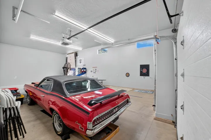 Garage featuring high ceilings, fluorescent lighting, an automatic garage door opener, and a white paneled garage door