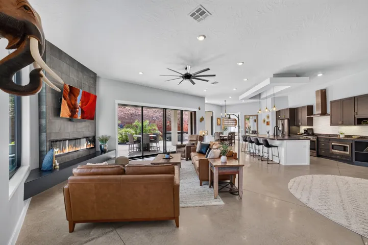 Open-concept living area with concrete flooring, a linear fireplace, and a kitchen island with seating