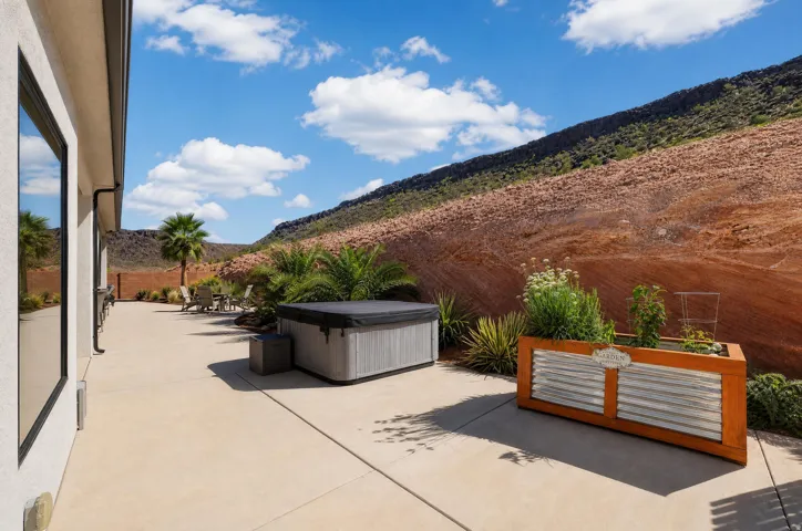 Expansive concrete patio featuring a hot tub and a raised garden planter