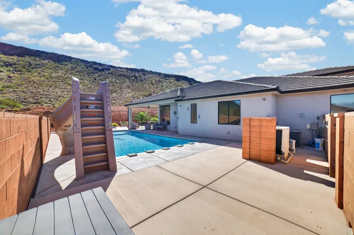 Enclosed concrete patio featuring a built-in swimming pool and a waterslide
