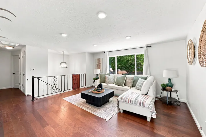 Hardwood flooring, recessed lighting, expansive window with natural light, decorative wrought iron railing, and a modern pendant light fixture