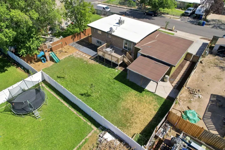 Expansive lawn area with a privacy fence, wood deck, and an attached covered patio