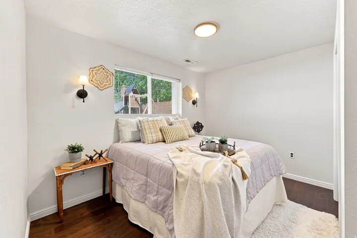 Hardwood-style flooring with white baseboards, a flush-mount ceiling light, and wall sconces