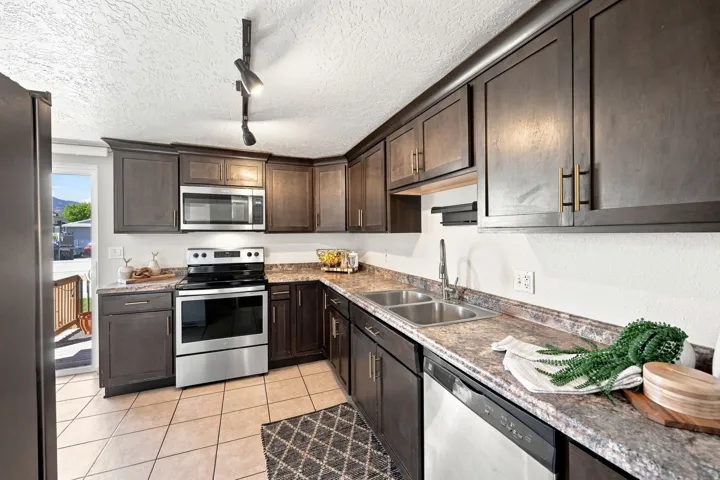 L-shaped kitchen featuring wood-finish cabinetry and a dual basin stainless steel sink