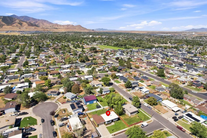 Residential neighborhood with established homes and mature trees, featuring a prominent mountainous backdrop and clear skies