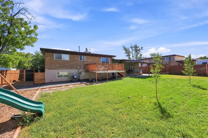 Expansive backyard featuring a manicured lawn, wood fencing, and a multi-level wood deck