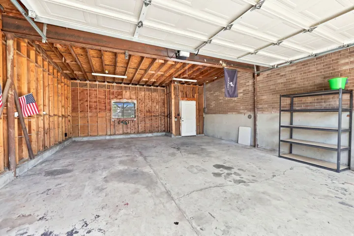 Concrete flooring with exposed wood framing, brick wall, and overhead garage door