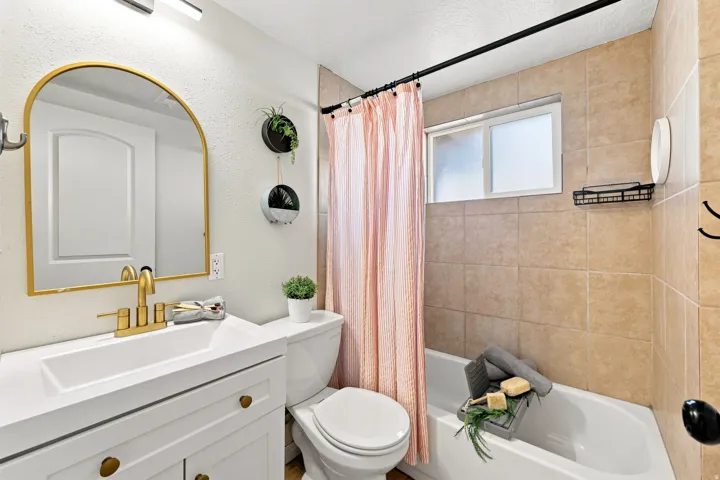 White vanity with gold-finish hardware, gold-finish faucet, and an arched mirror