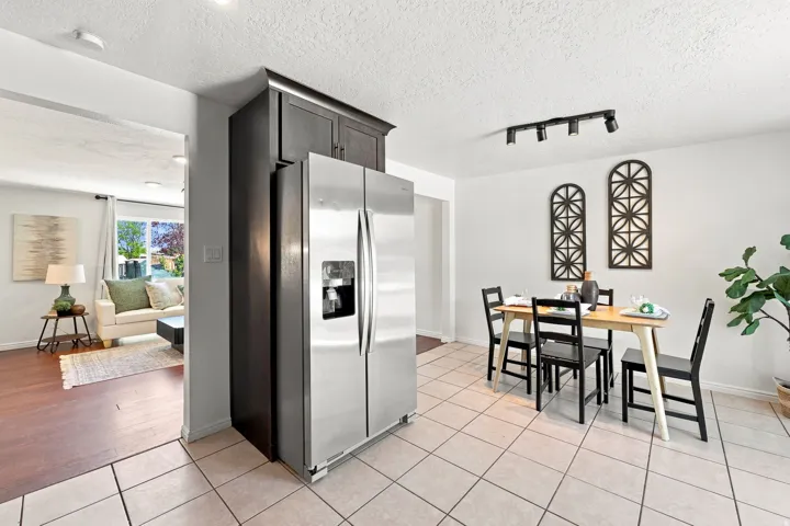 Stainless steel French door refrigerator, dark wood-finish cabinetry, tile flooring, track lighting, and wood-finish flooring