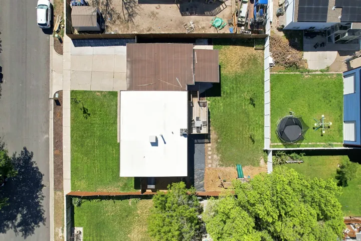 Spacious lot featuring front and rear lawn areas, a large rear patio, and a dedicated driveway