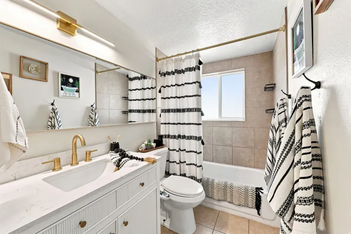 Single vanity with integrated sink, gold-finish fixtures, and a wall-mounted mirror