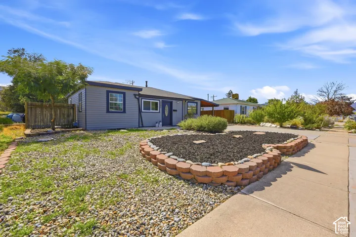Siding exterior with contrasting trim, front entry door, and a landscaped front yard featuring a planting bed with decorative stones