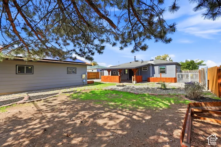 Spacious backyard with a covered patio, wood deck, fenced perimeter, and established landscaping