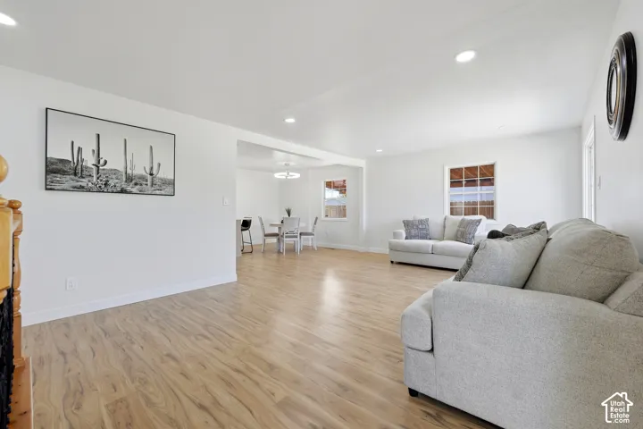 Recessed lighting illuminates the open living area featuring wood-finish flooring and white walls