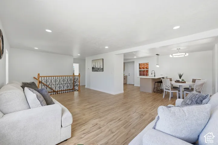 Expansive room featuring wood-finish flooring, recessed lighting, and a white color palette