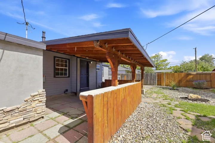 Covered patio featuring exposed wood beams, a paved surface, and stone accents