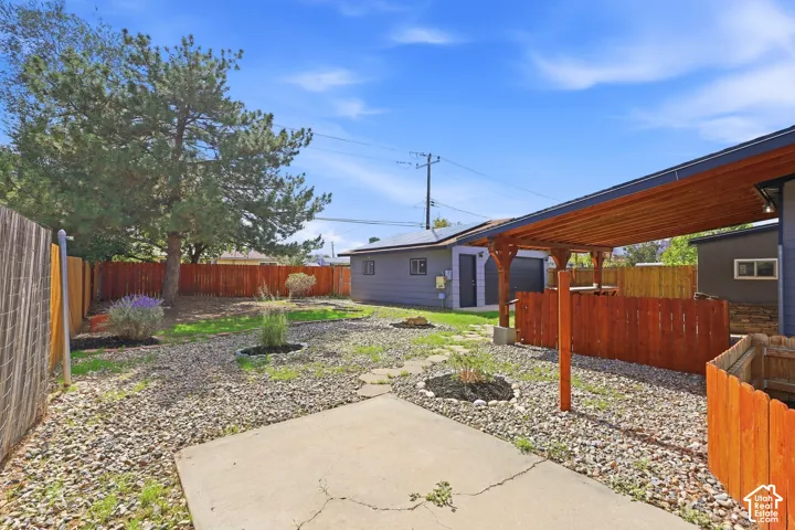 Expansive backyard featuring a concrete patio, a wood-finish fence, and a covered patio structure