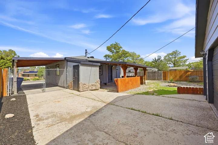 Carport structure, privacy fencing, stone veneer accents, concrete patio, and exterior siding