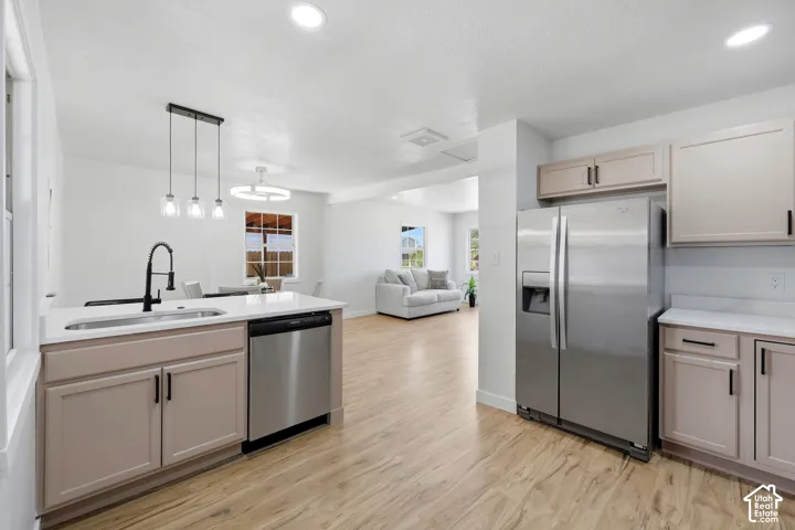 Modern kitchen featuring light-toned cabinetry, stainless steel appliances, wood-finish flooring, and recessed lighting