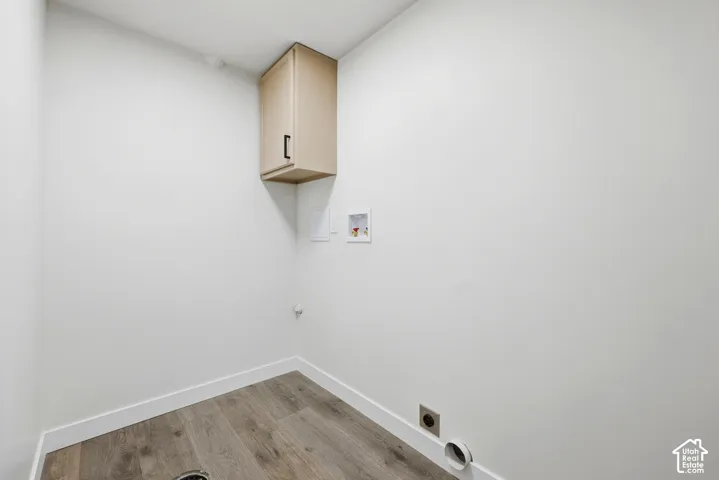 Wood-finish flooring with white wall base molding, featuring a built-in upper cabinet with matte black hardware