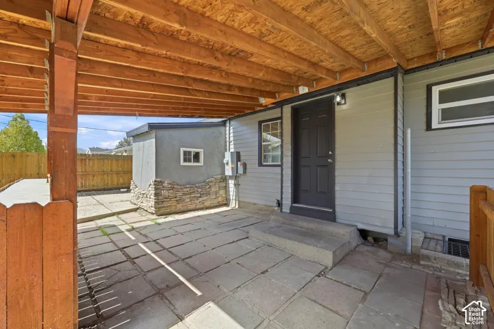 Covered patio with stone pavers and exposed wood ceiling beams