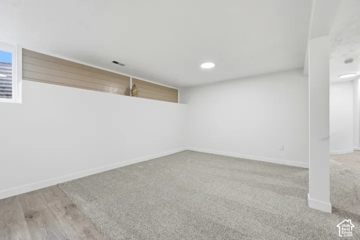 Recessed lighting, light grey carpeting, white walls, built-in shelving, wood-finish flooring