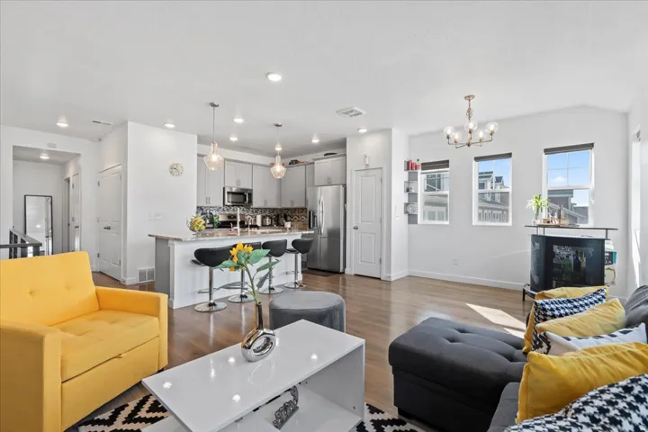 Open-concept living space featuring wood-finish flooring, a kitchen island with seating, stainless steel appliances, and recessed lighting