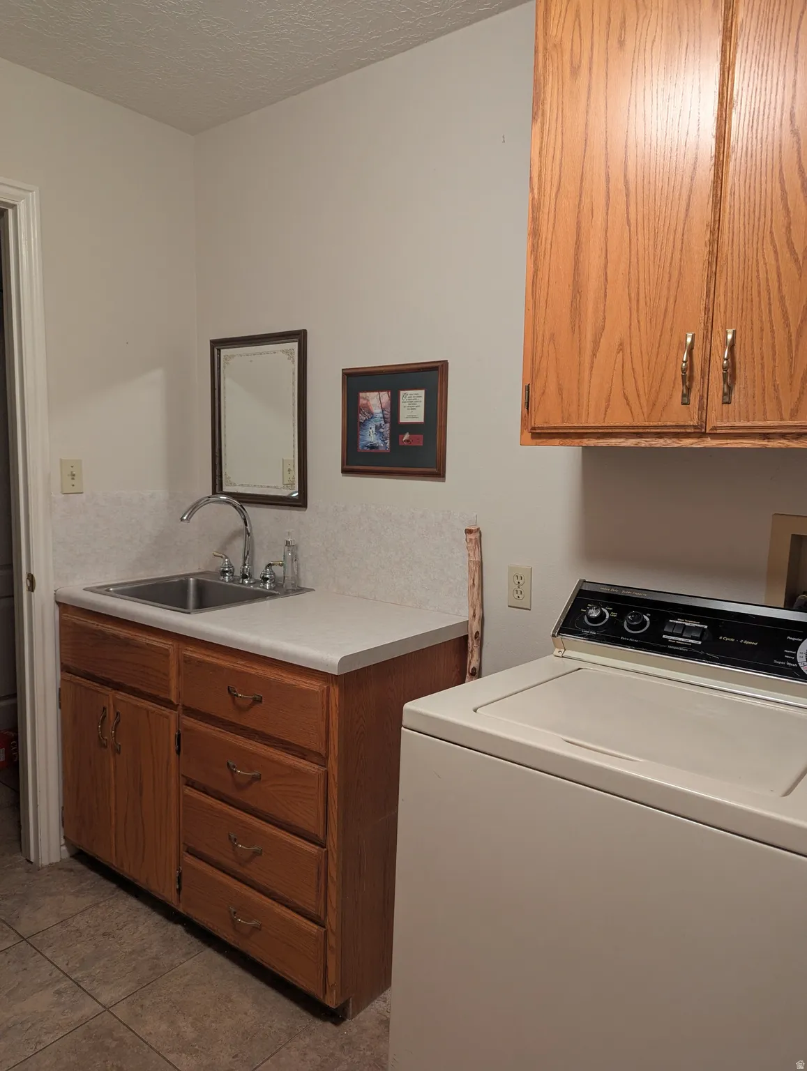 Laundry area featuring a utility sink, solid surface countertop, and wood-finish cabinetry