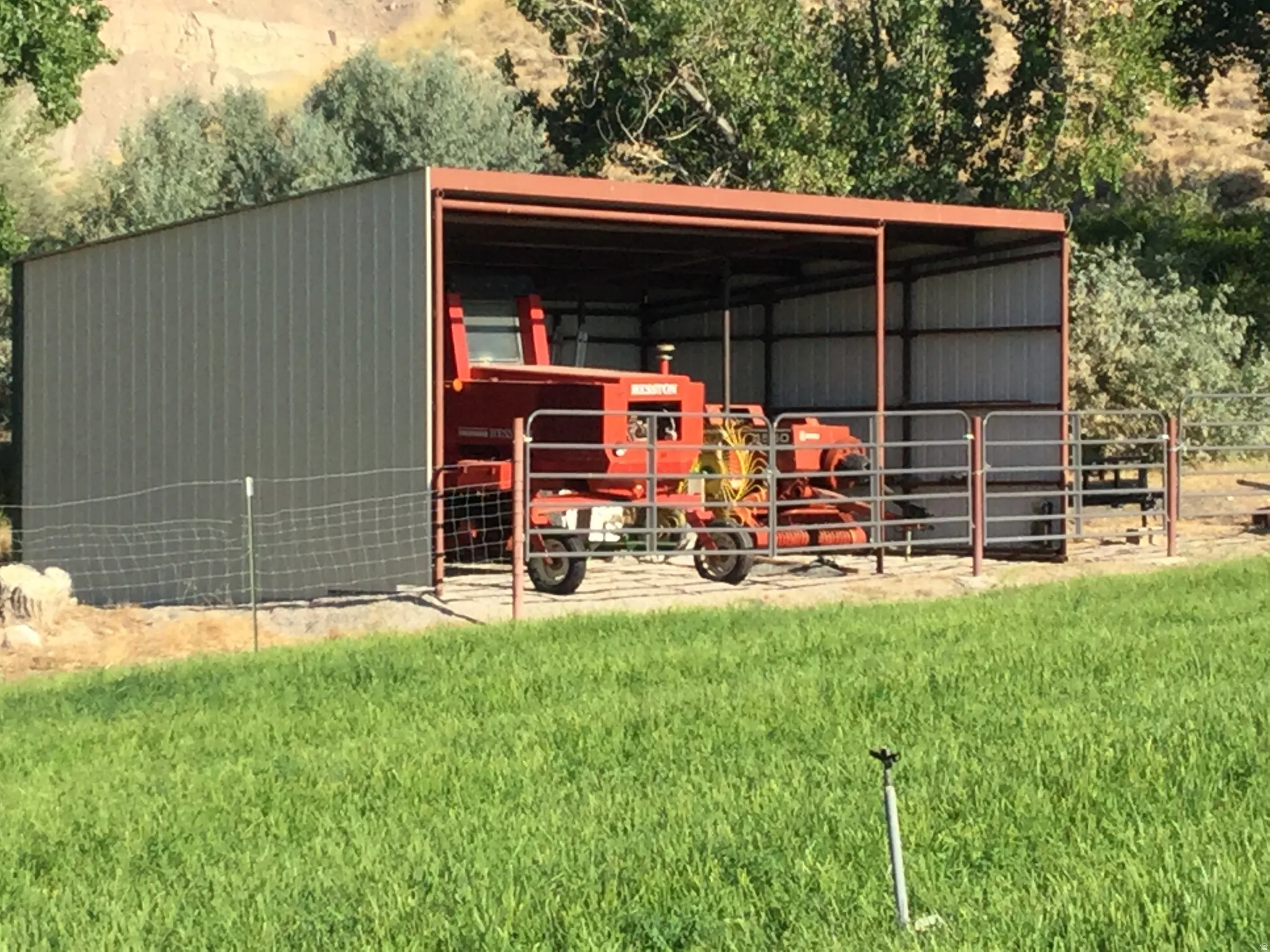 Metal-sided outbuilding with an open-air bay, corrugated metal roof, and durable metal fencing