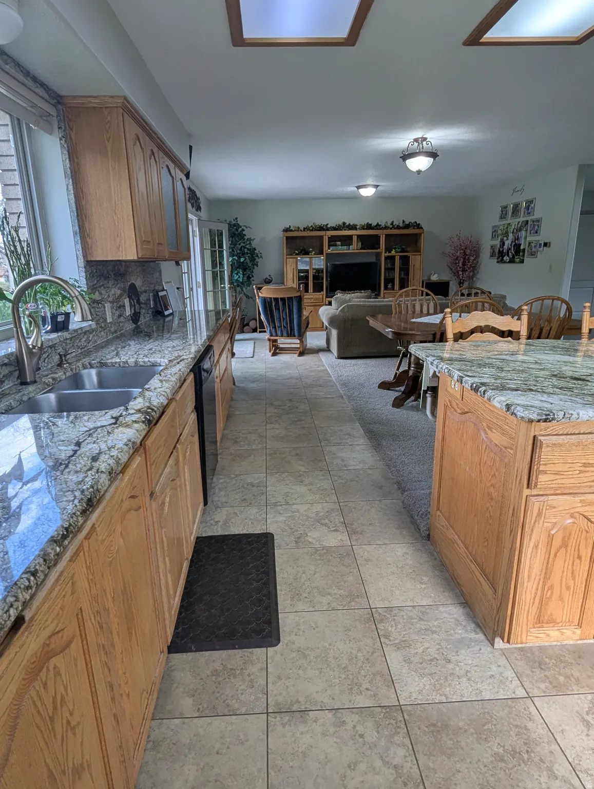 Kitchen featuring a double basin sink, light wood-finish cabinetry, and granite countertops