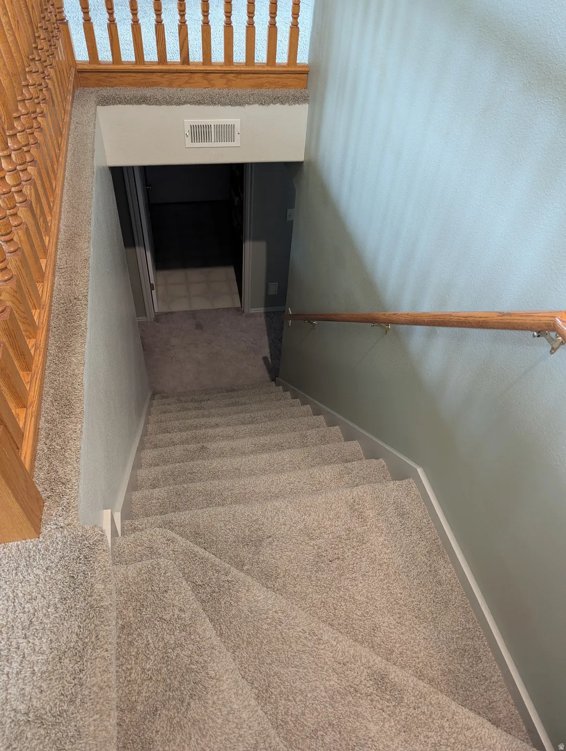Carpeted staircase with wood handrails and balusters