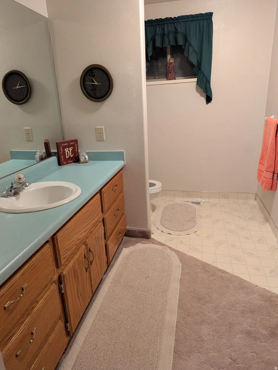 Vanity with integrated sink, wood-finish cabinetry, and a light-colored countertop