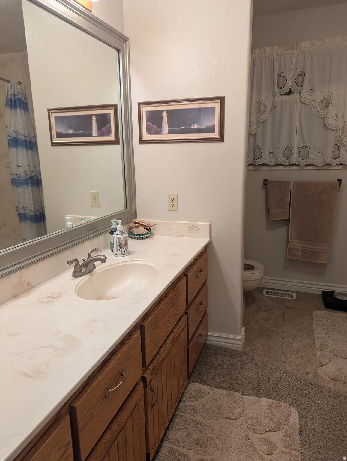 Single vanity with an integrated sink, patterned countertop, and wood-finish cabinetry