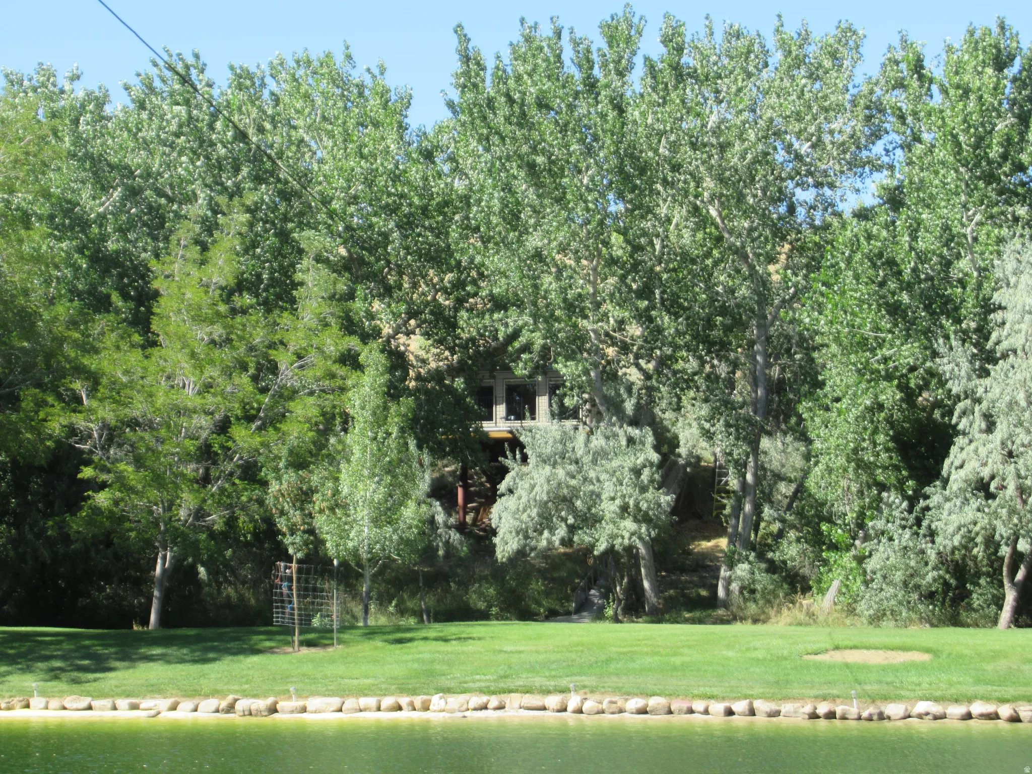 Expansive grassy lawn with a natural pond and stone-lined edge