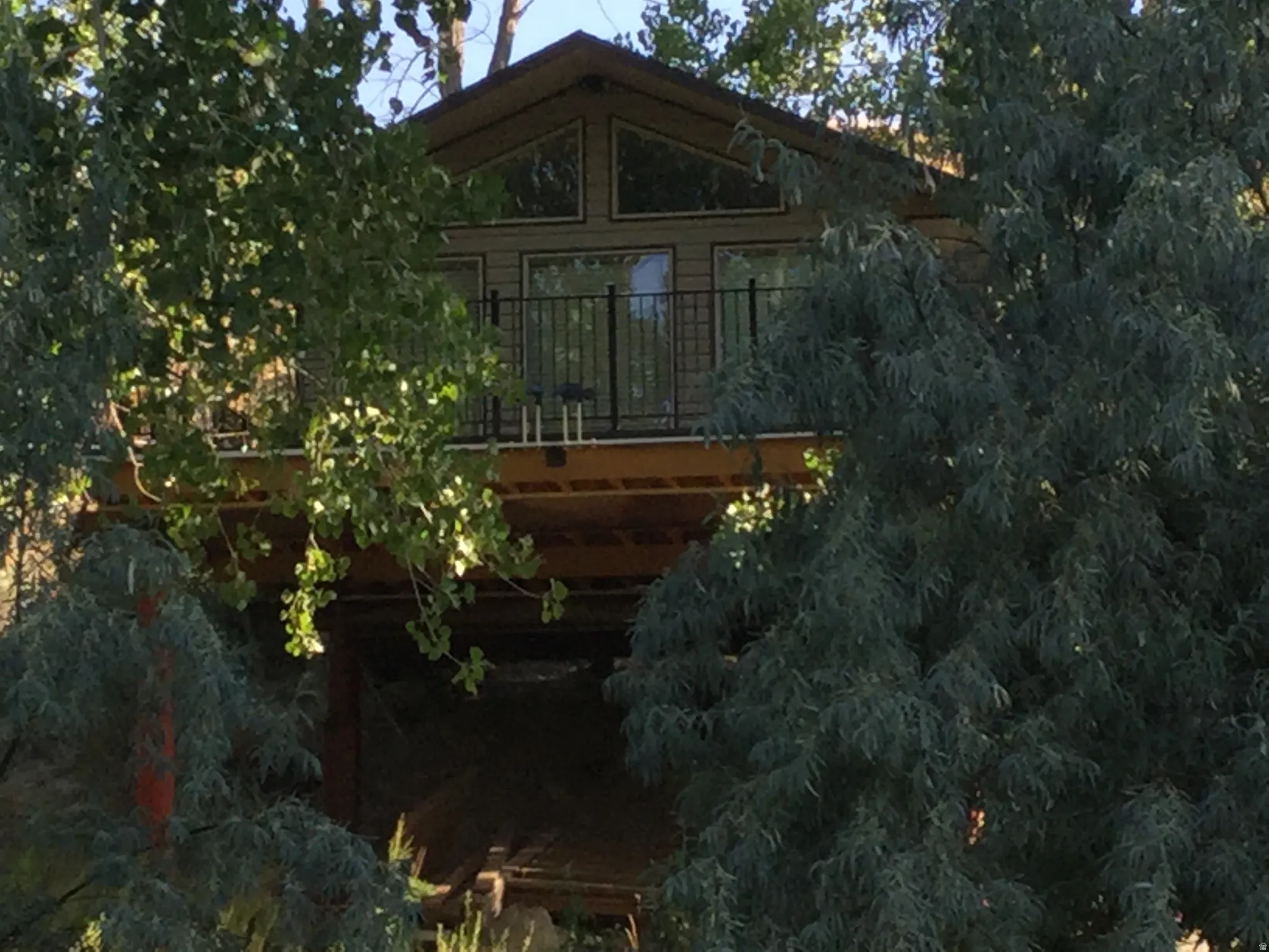 Exterior featuring a peaked roof, upper-level balcony with metal railing, and horizontal siding