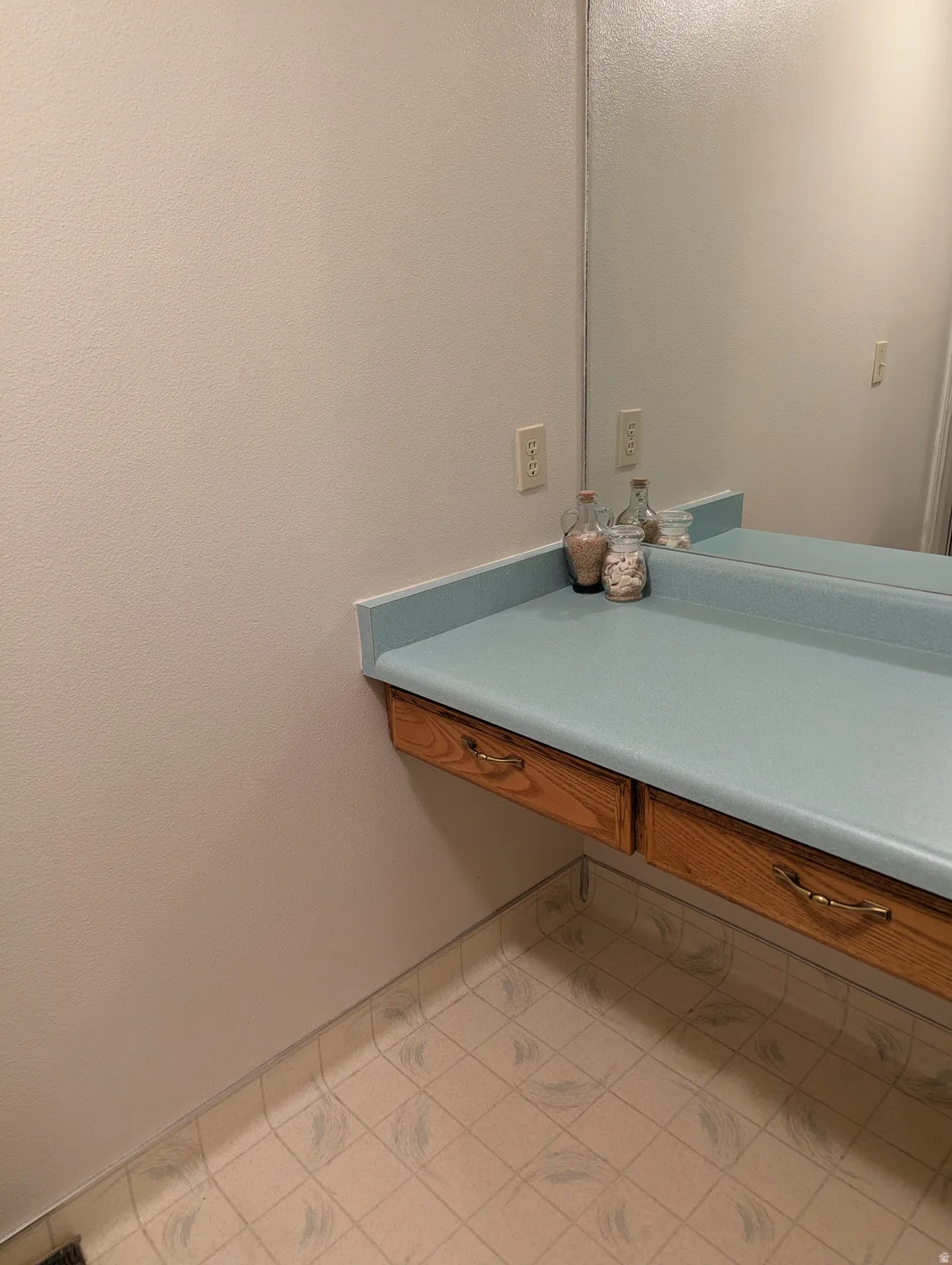 Floating vanity with integrated storage drawers, light blue countertop, and a large wall-mounted mirror