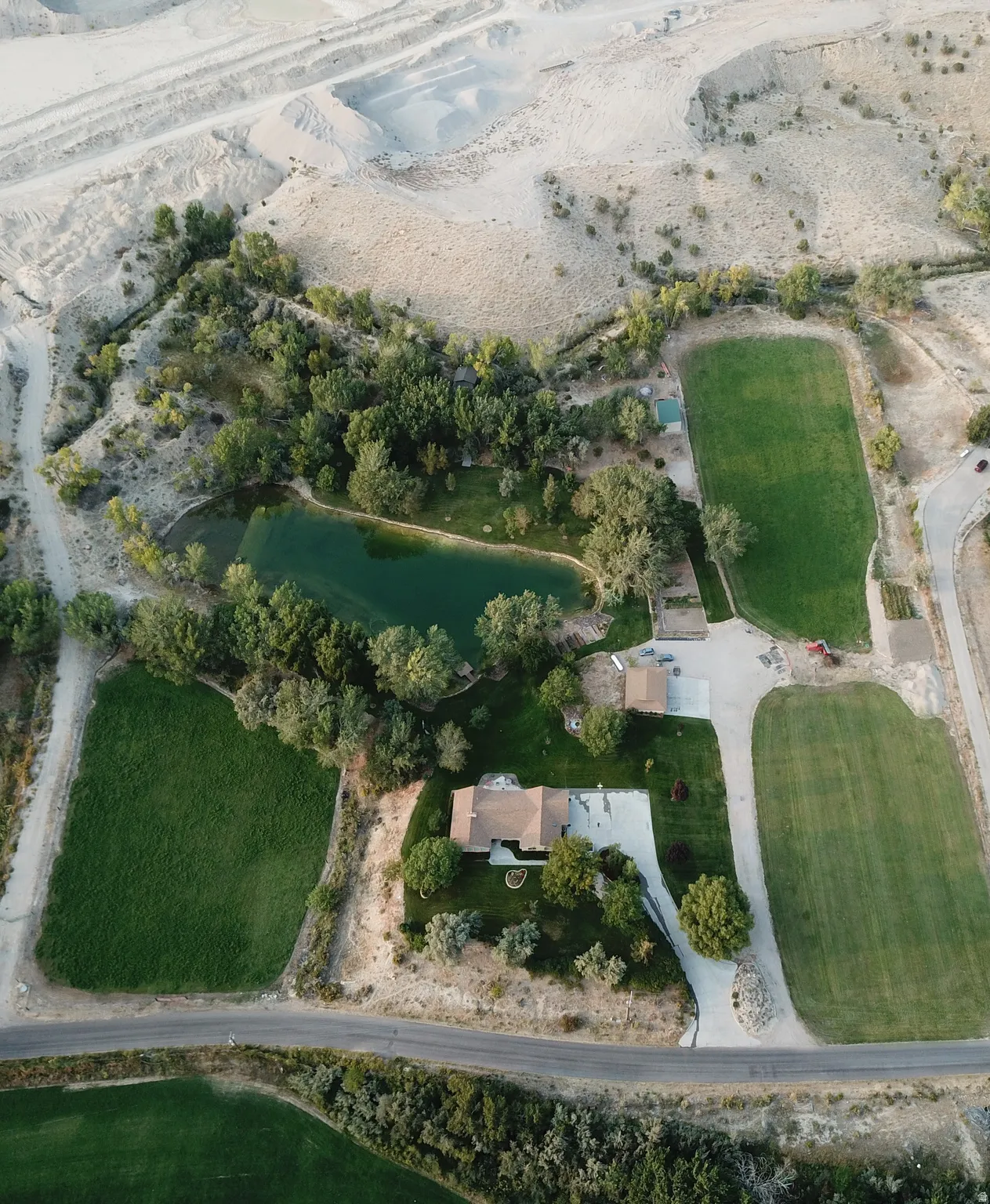 Expansive grounds featuring a private pond, mature trees, manicured lawns, and a private driveway