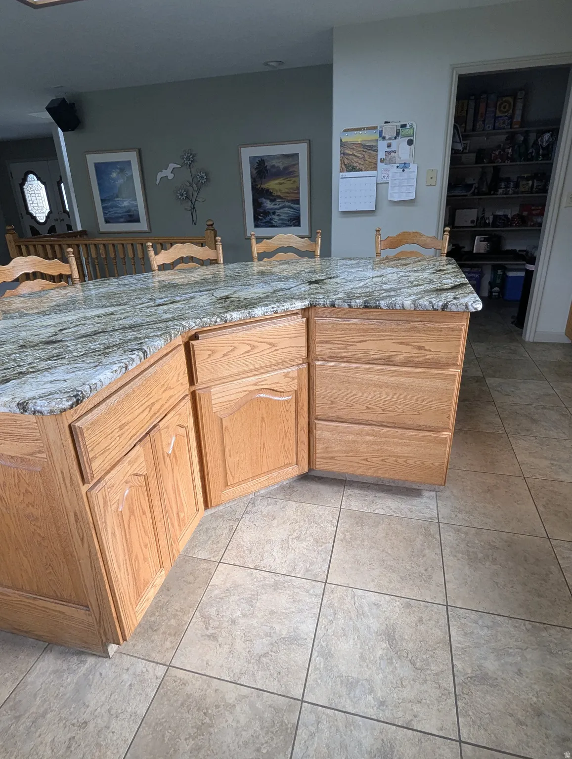 Kitchen island featuring a stone-finish countertop, wood cabinetry, and tile flooring