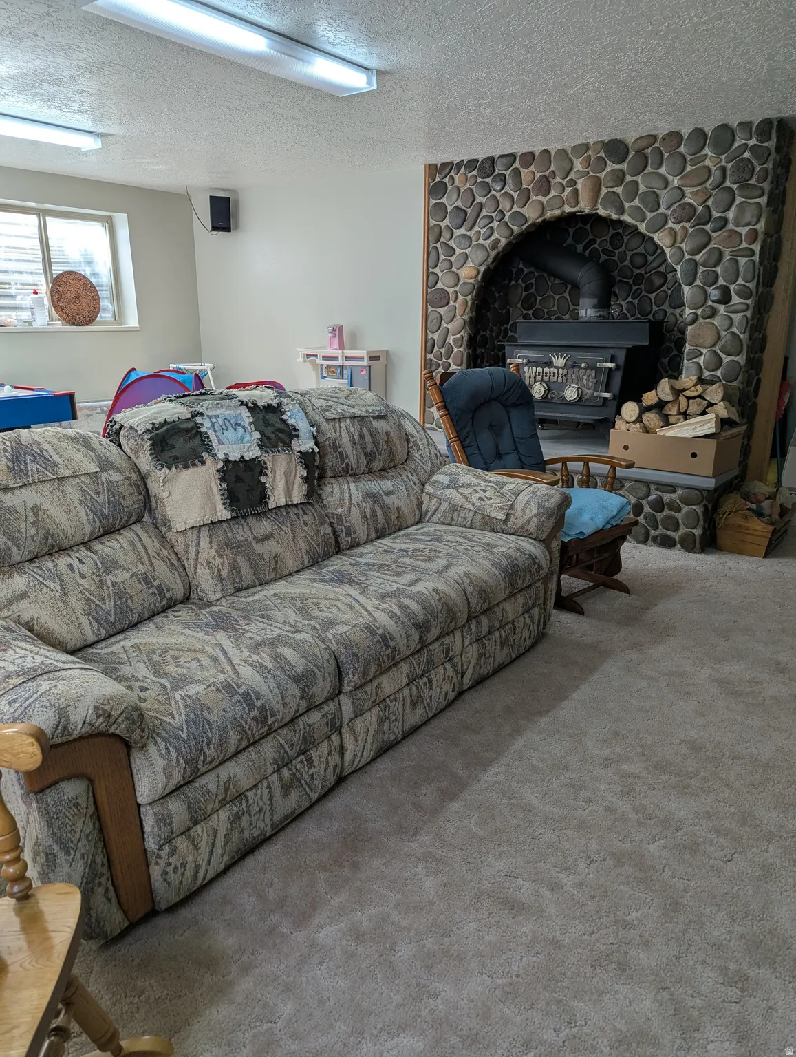 River rock fireplace surround with an arched opening, featuring a wood-burning stove