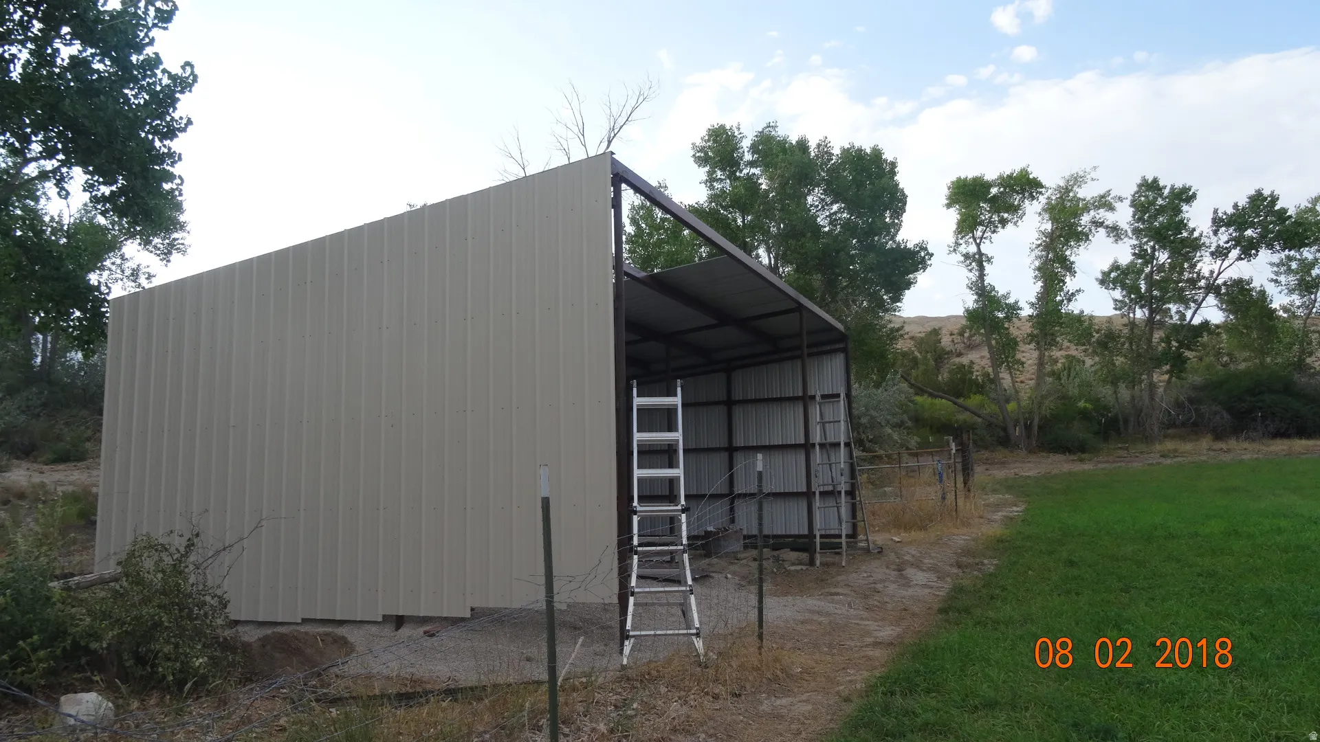 Metal-sided outbuilding with an open-sided design, metal roof, and a gravel base