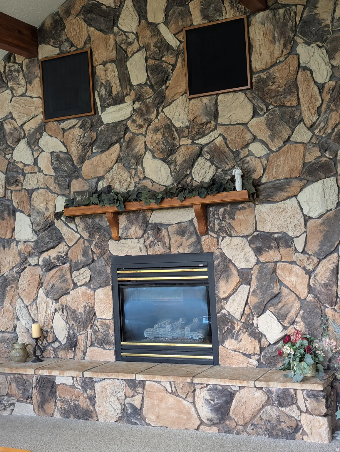 Floor-to-ceiling stone fireplace featuring a built-in firebox, stone hearth, and a wood mantel