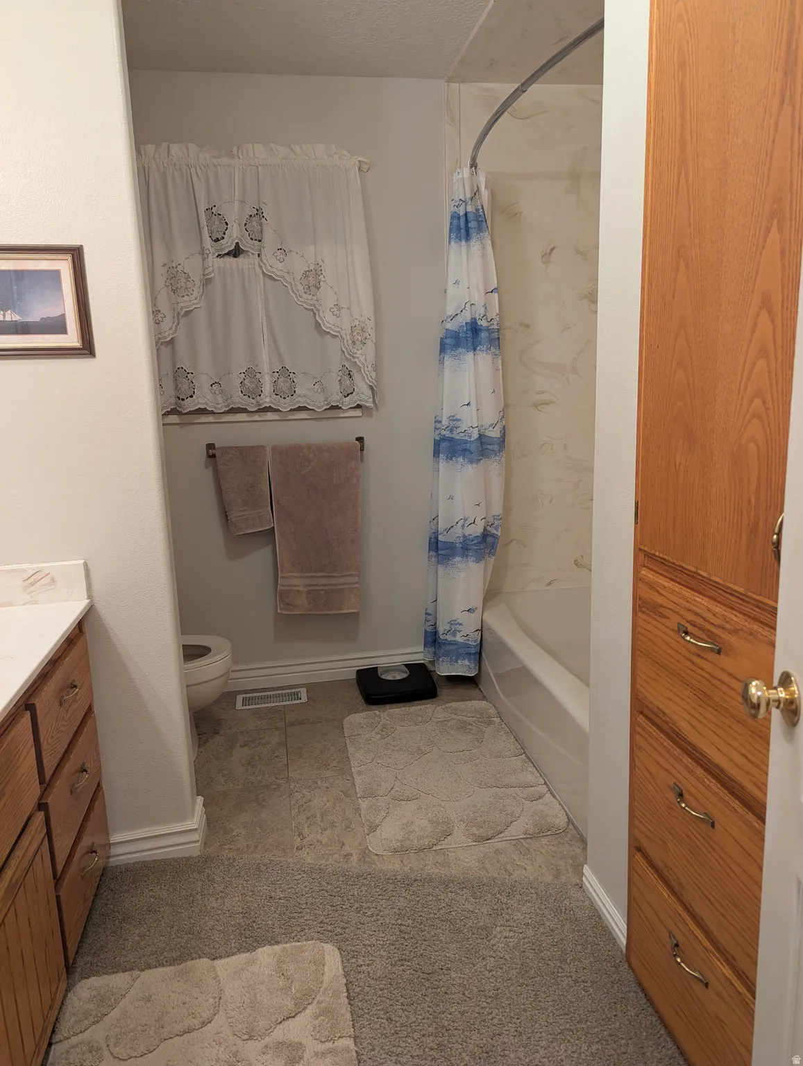 Built-in cabinetry with wood-finish drawers, tile flooring, and a bathtub with a shower