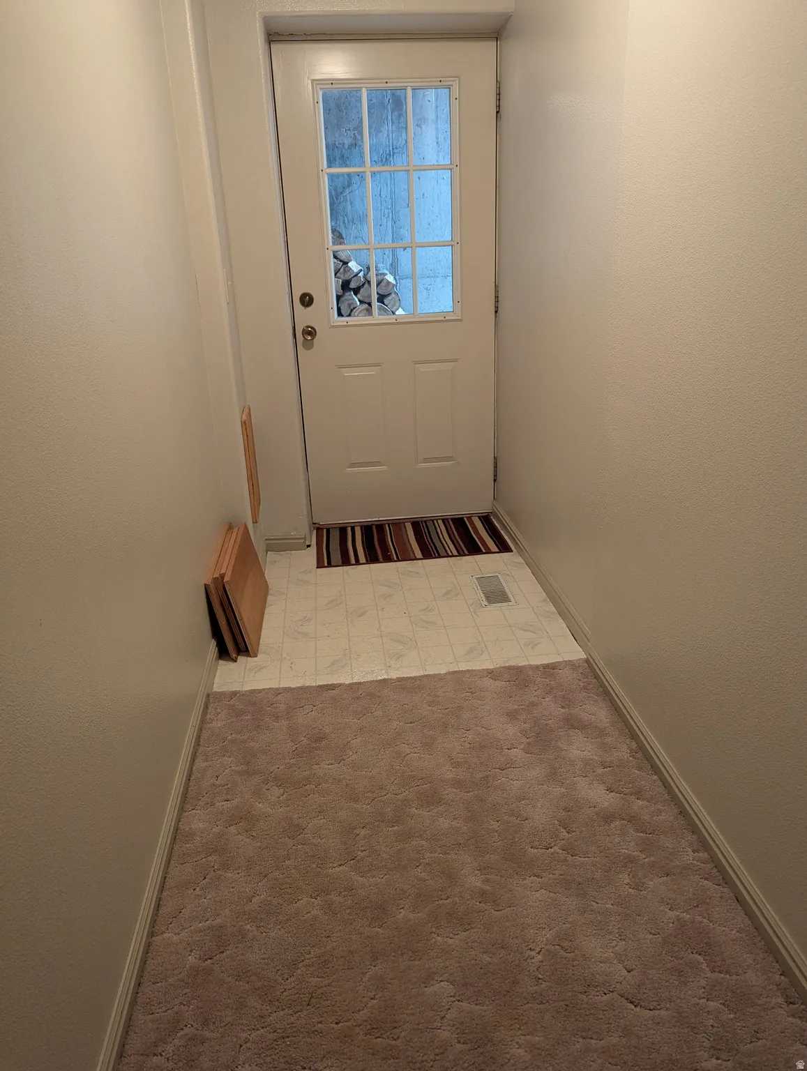 White paneled door with divided lite glass, extending to a tiled floor transition