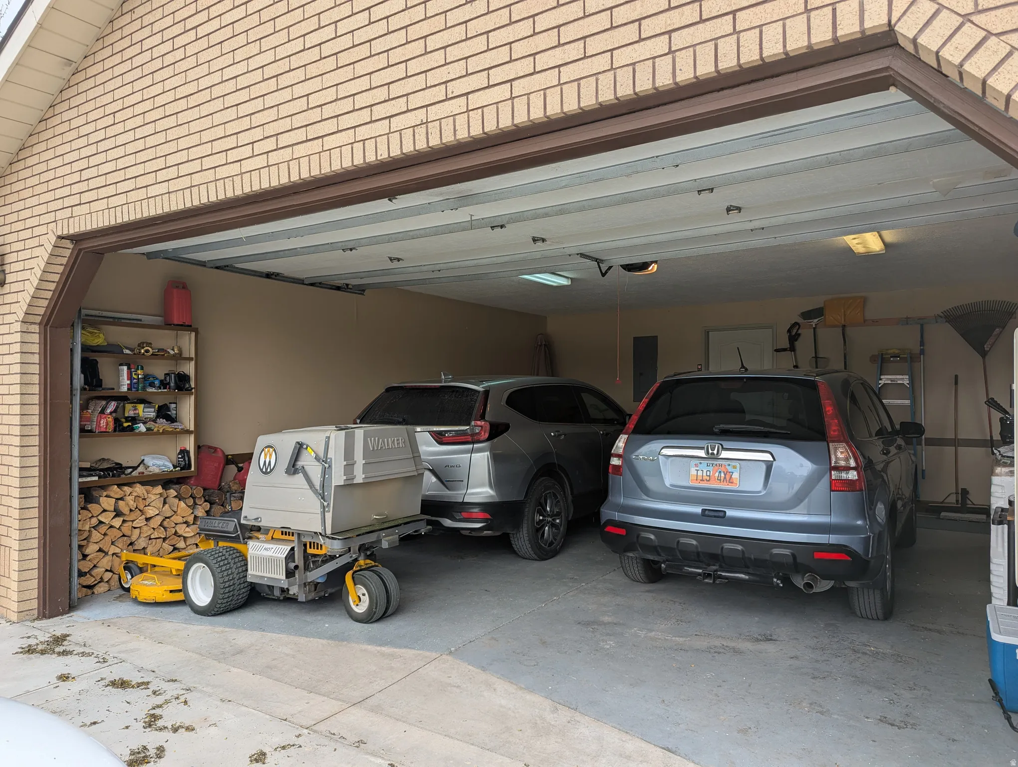 Attached two-car garage with a concrete floor, brick exterior, and a built-in shelving unit