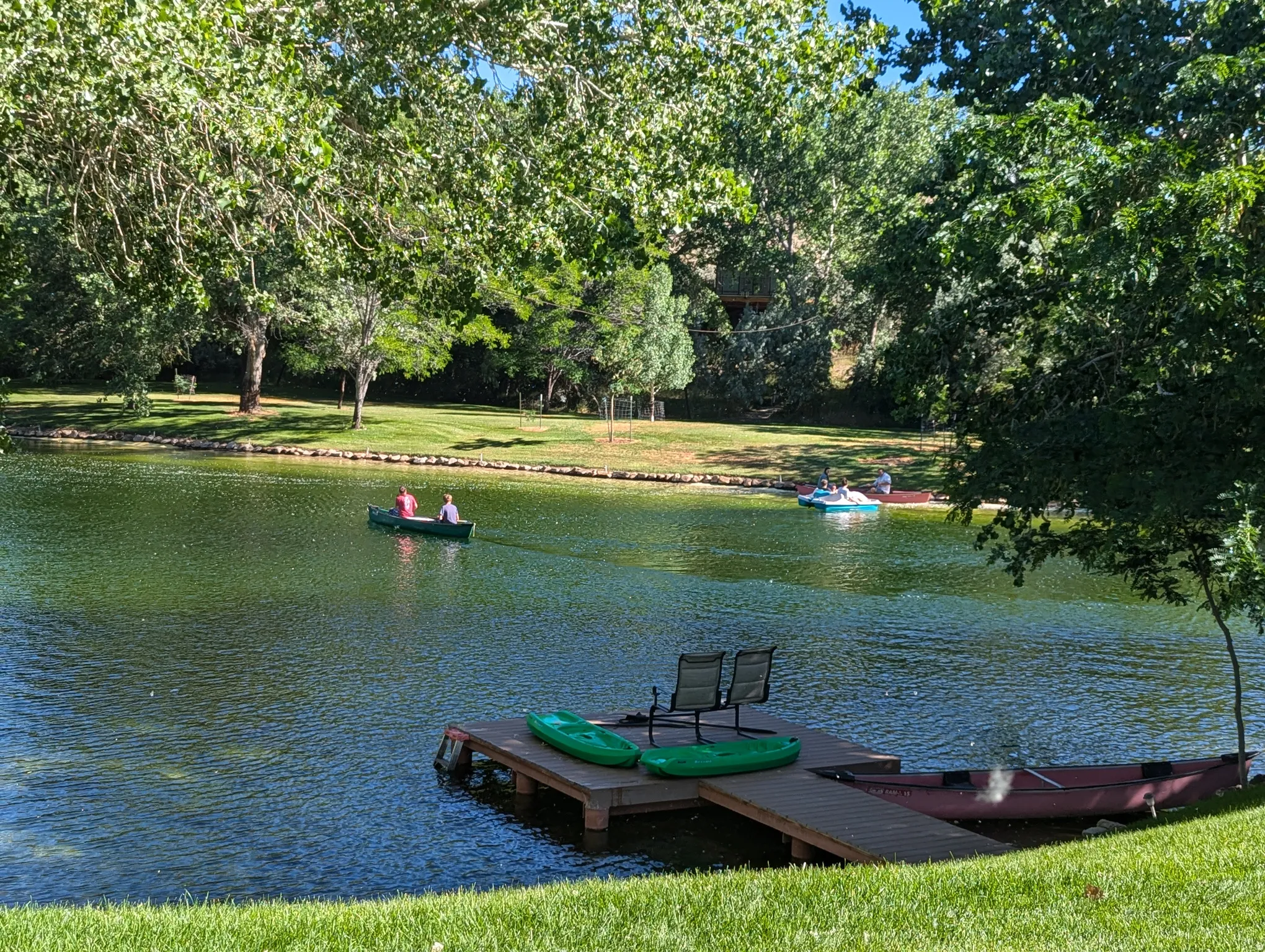Expansive water feature with a wooden dock, surrounded by mature trees and manicured green space
