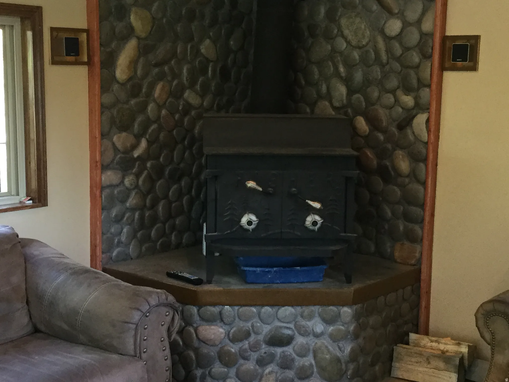 Stone-clad fireplace feature with a built-in wood-burning stove and a wood mantel